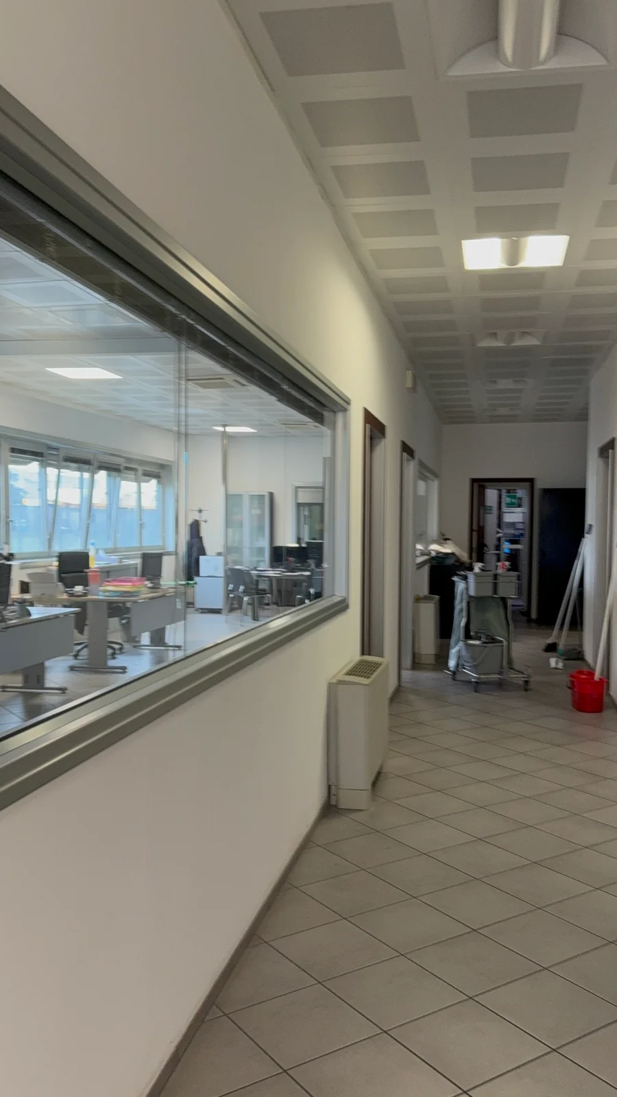 Corridoio di uffici con pareti vetrate e attrezzature per la pulizia